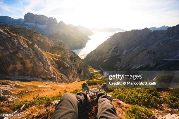 personal perspective of man sitting on top of a mountain admiring the sunrise, italy - shoes top view stockfoto's en -beelden