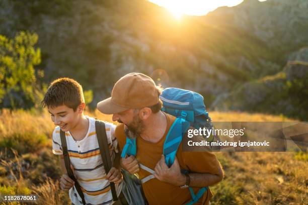 teenage boy and mature man on sunny day on mountain ridge - hiking mature man stock pictures, royalty-free photos & images