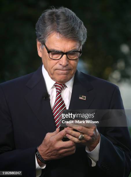 Secretary of Energy Rick Perry looks at his phone before appearing on a morning television show, at the White House on October 23, 2019 in...