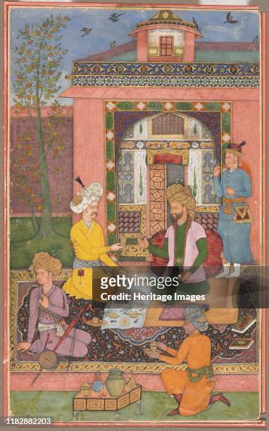 Feast in a pavilion setting, circa 1620. Two gentlemen sit on a low carpeted platform in a walled garden. They wear bulbous turbans meant to indicate...