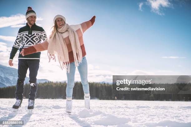 冬の楽しみを楽しむ凍った湖に手をつないで幸せな若いカップルのアイススケート - アイススケート ストックフォトと画像