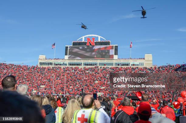 Fans watch as two Blackhawk helicopters perform a flyover before the start of the game between the Nebraska Cornhuskers and the Wisconsin Badgers at...