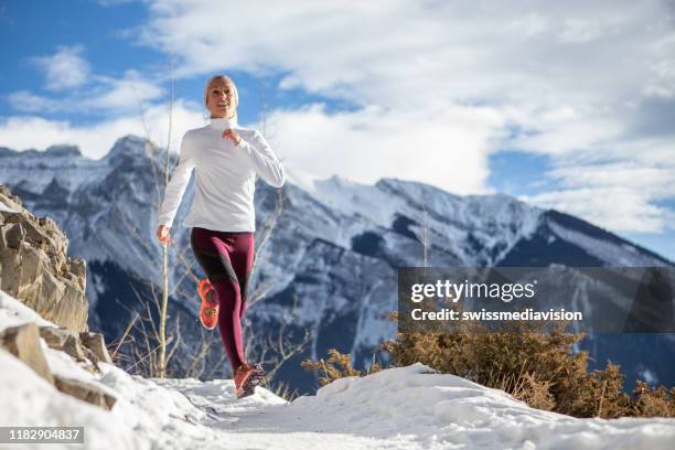 mujer haciendo ejercicio para correr a campo traviesa en invierno trotando sobre la nieve - cross country running fotografías e imágenes de stock