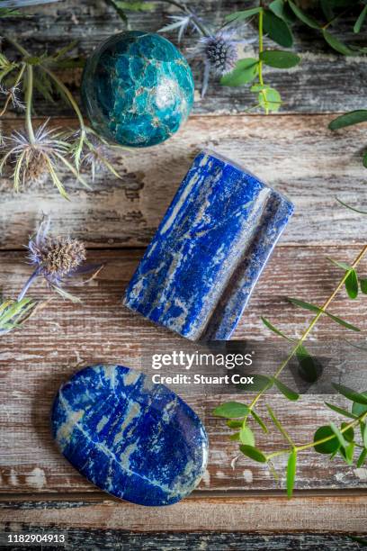 blue apatite, lapis lazuli and sodalite surrounded by thistles, eucalyptus on a rustic wooden background - lapis fotografías e imágenes de stock