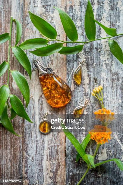 amber pendants set in silver on a rustic wooden background. - kristallheilung stock-fotos und bilder