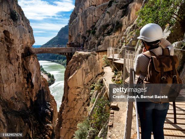 hiker in the nature walking on a wooden footbridge, nailed on the walls of rock in a gorge to great height. caminito del rey (the king walkway). - caminito del rey málaga province stock pictures, royalty-free photos & images