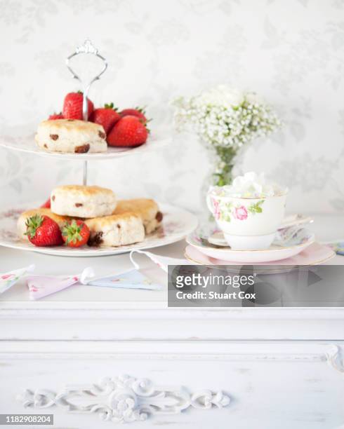 still life of a traditional cream tea with scones, jame, strawberries, cream and flowers - teatime english stock-fotos und bilder