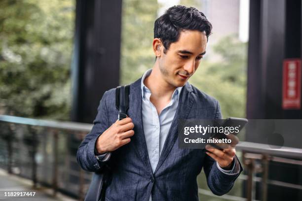 businessman text messaging on mobile phone - hearing aid stock pictures, royalty-free photos & images