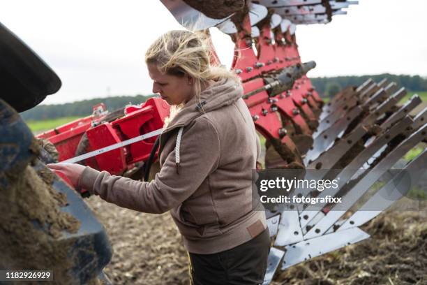landwirtin repariert einen pflug auf einem landwirtschaftlichen feld - landwirtschaft deutschland stock-fotos und bilder