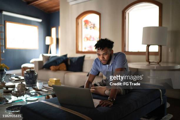geamputeerde jonge man kijken naar film op een laptop thuis - latina legs stockfoto's en -beelden