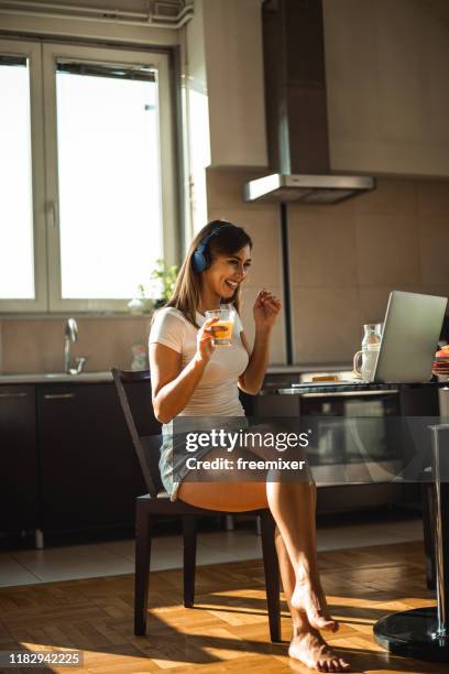 mooie jonge vrouw luisteren muziek in appartement - mango juice stockfoto's en -beelden