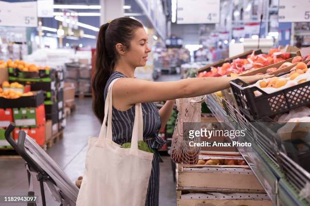 woman with grocery eco bag of vegetables in a supermarket background. - reusable bag stock pictures, royalty-free photos & images