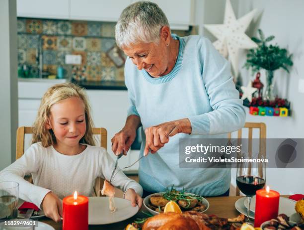 senior woman serving roasted turkey to her lovely granddaughter. - portion stock pictures, royalty-free photos & images