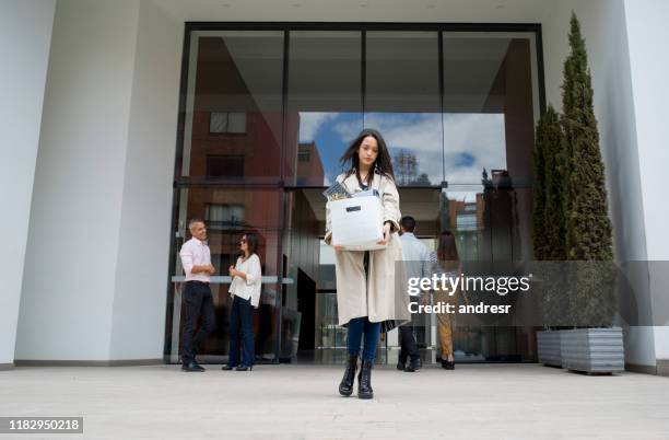 fired woman leaving the office with her belongings in a box - quitting a job stock pictures, royalty-free photos & images