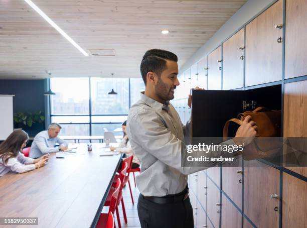 entrepreneur at a co-working space putting his briefcase in a locker - locker stock pictures, royalty-free photos & images