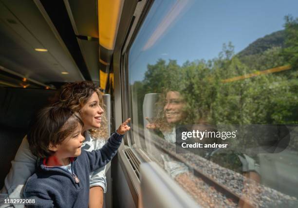 mother and son riding on the train and looking through the window - riding stock pictures, royalty-free photos & images