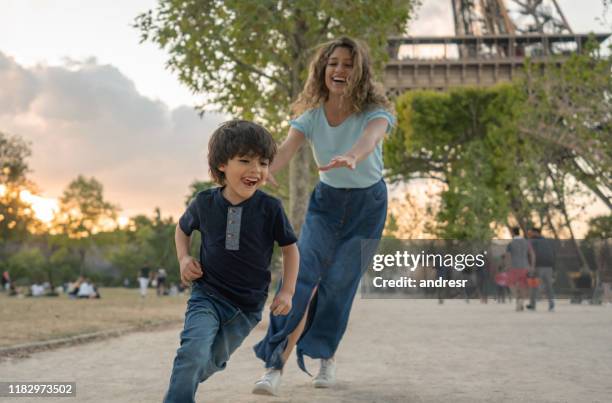 glückliche mutter und sohn spielen in paris in der nähe des eiffelturms - verfolgen stock-fotos und bilder