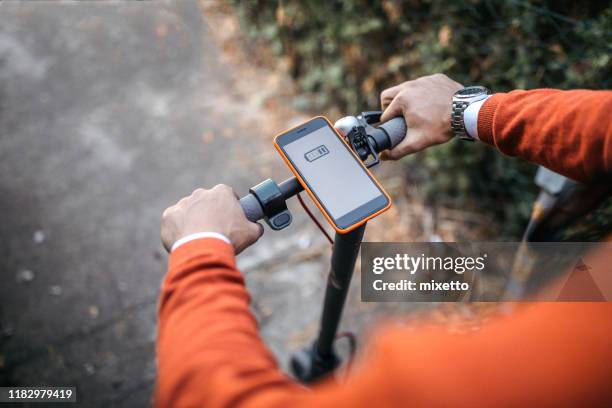 uomo con scooter elettrico e cellulare - veicolo elettrico automobile con biodiesel foto e immagini stock