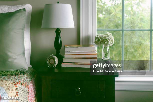 nightstand with pile of books, alarm clock and lamp next to bed - bedside table stock pictures, royalty-free photos & images