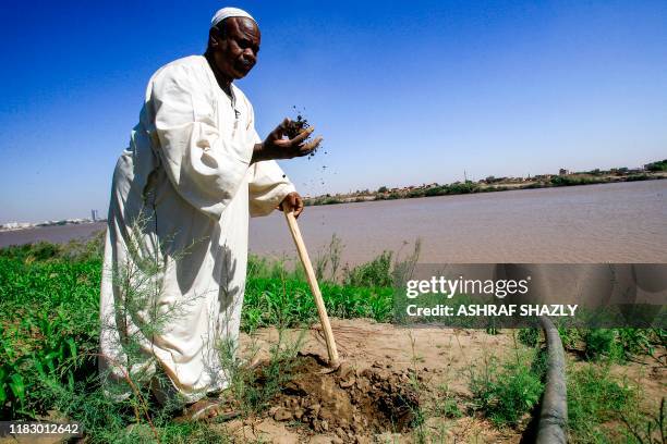 Osman Idris, a 60-year-old Sudanese farmer, holds a piece of soil during an interview with AFP in an agricultural field in the capital Khartoum's...