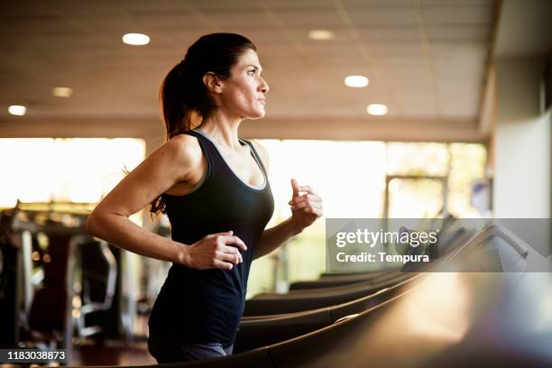 middle-aged woman running in a treadmill and listening to music. - 40 2018 stock pictures, royalty-free photos & images