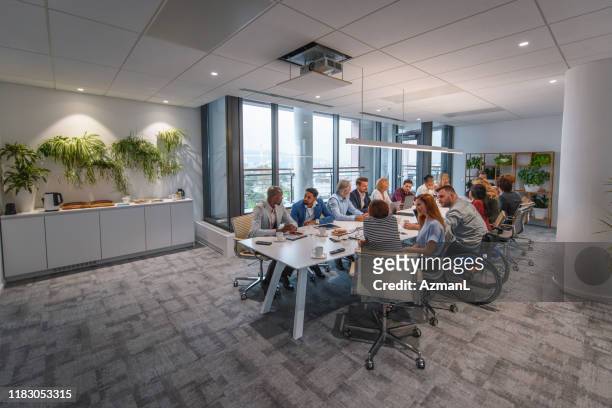 squadra esecutiva seduta al tavolo della conferenza nella sala consenzi - coinvolgimento dei dipendenti foto e immagini stock