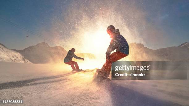 hombre y mujer practicando snowboard en la montaña - snowboarding fotografías e imágenes de stock