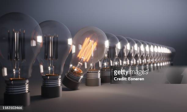 glowing light bulb standing out from the crowd - change management imagens e fotografias de stock