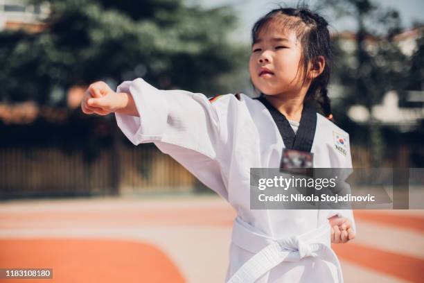 nettes kleines mädchen in kimono training karate punsch - karate girl stock-fotos und bilder