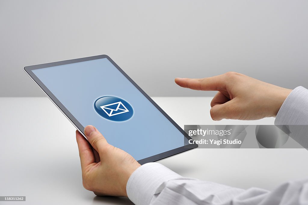 Man tapping on e-mail symbol on tablet computer