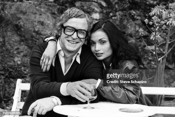 Portrait of married actors Michael Caine and Shakira Caine as they sit on a bench outside their home, Los Angeles, California, 1982.