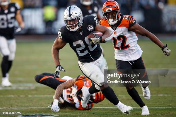 Running back Josh Jacobs of the Oakland Raiders rushes past free safety Jessie Bates of the Cincinnati Bengals and cornerback William Jackson during...