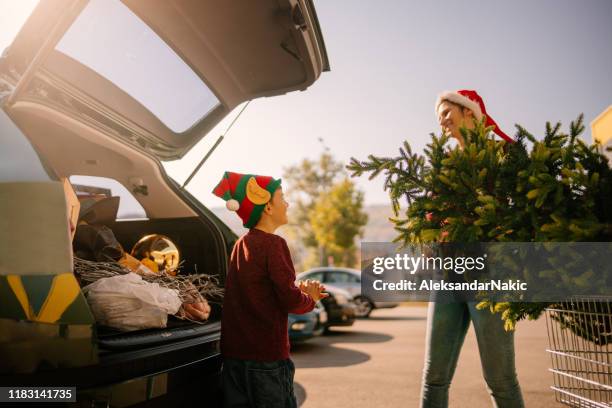 mutter und sohn packen ihren weihnachtsbaum - car shopping stock-fotos und bilder