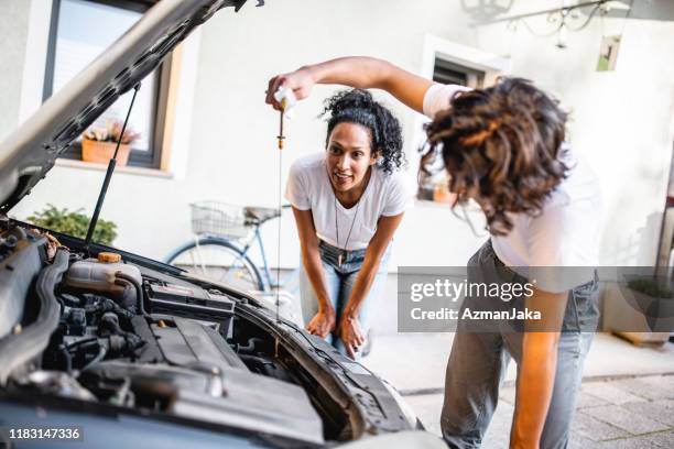 hispanische mutter beobachtet ihren sohn überprüfen das öl im auto - car repairs stock-fotos und bilder