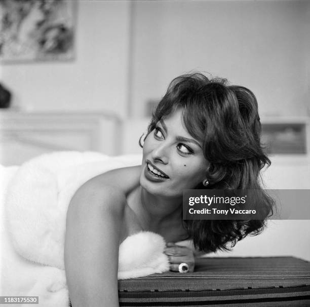 Italian actress Sophia Loren lies down on her stomach wearing a white fur shawl around her chest, New York City, US, 1954.