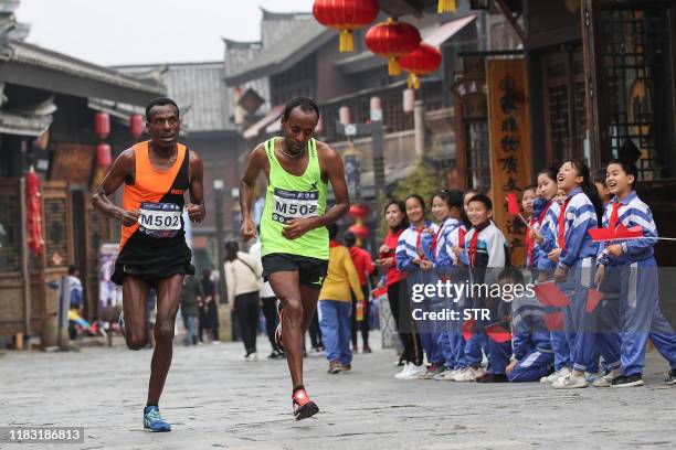 This photo taken on November 17, 2019 shows runners cheered by students during the Guizhou Tour of Leigong Mountain 100km International Marathon in...