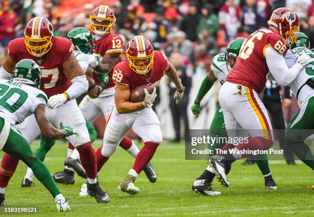 Washington Redskins running back Derrius Guice hits a hole made by offensive linemen Ereck Flowers and Tony Bergstrom during action against the New...