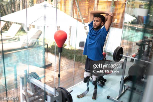 Portrait of young man with prosthetic leg stretching in gym