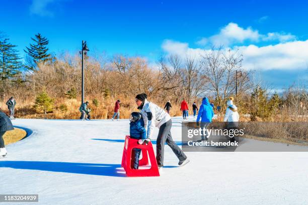 dad teaches child to ice skate with trainer - etobicoke ontario stock pictures, royalty-free photos & images