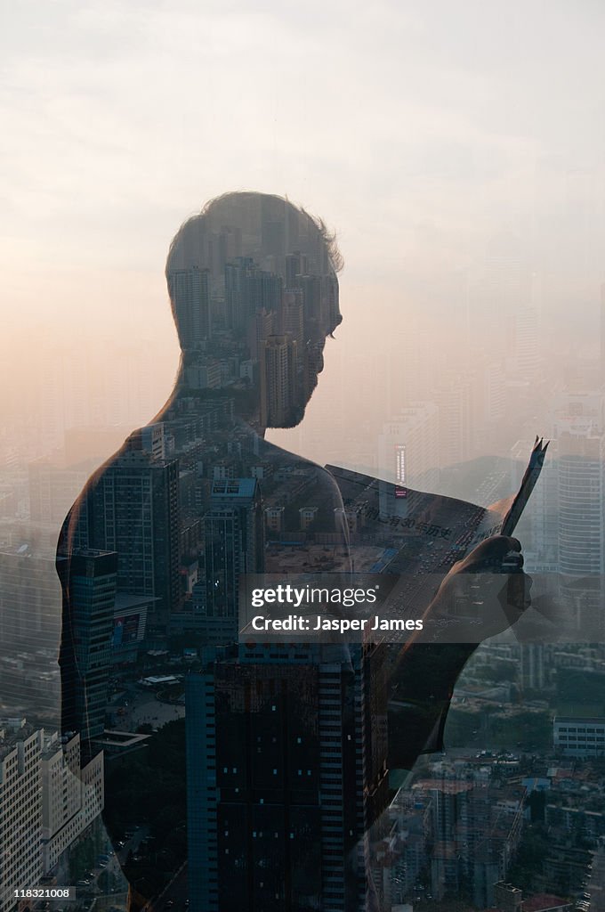 Double exposure of man reading newspaper and citys