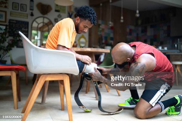 Personal trainer helping a young man with prosthetic leg