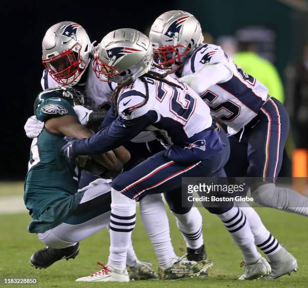 From left, New England Patriots defenders Ja'Whaun Bentley, Stephon Gilmore and Terrence Brooks combine to bring down Eagles wide receiver Nelson...