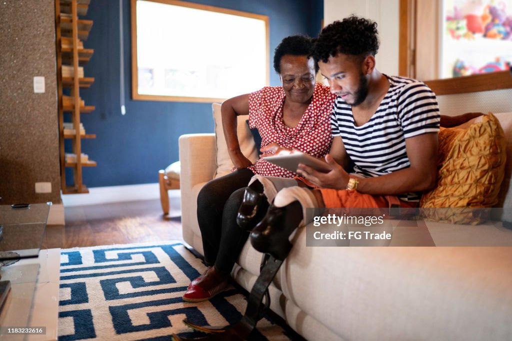 Fils/petit-fils utilisant la tablette numérique avec sa mère/grand-mère