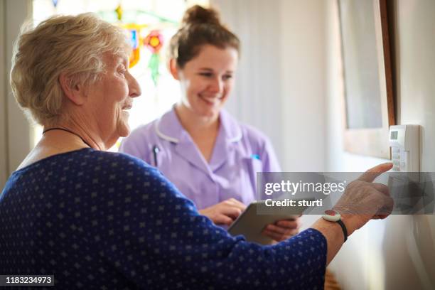 home carer zeigt seniorin ihre alarmtafel - panic button stock-fotos und bilder