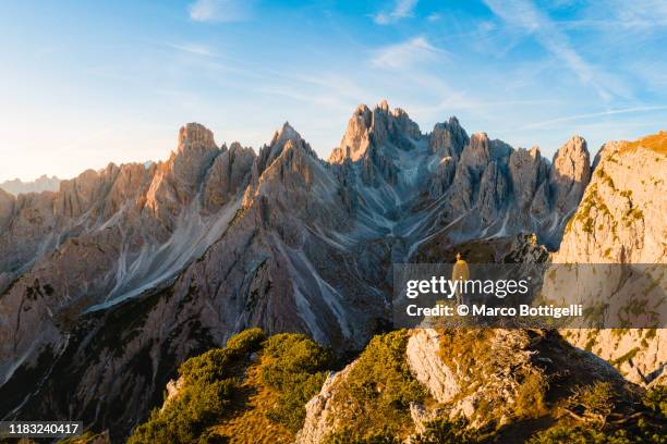 hiker admiring the dolomites at sunrise, italy - dolomites photos et images de collection