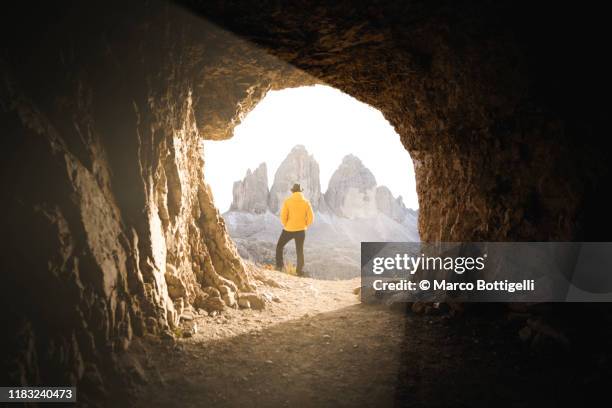 man at the end of tunnel admiring the three peaks of lavaredo, italy - light at the end of the tunnel stockfoto's en -beelden