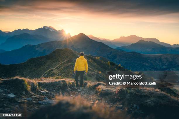 one person admiring the sunset on a mountain ridge, italy - behind sun stock pictures, royalty-free photos & images