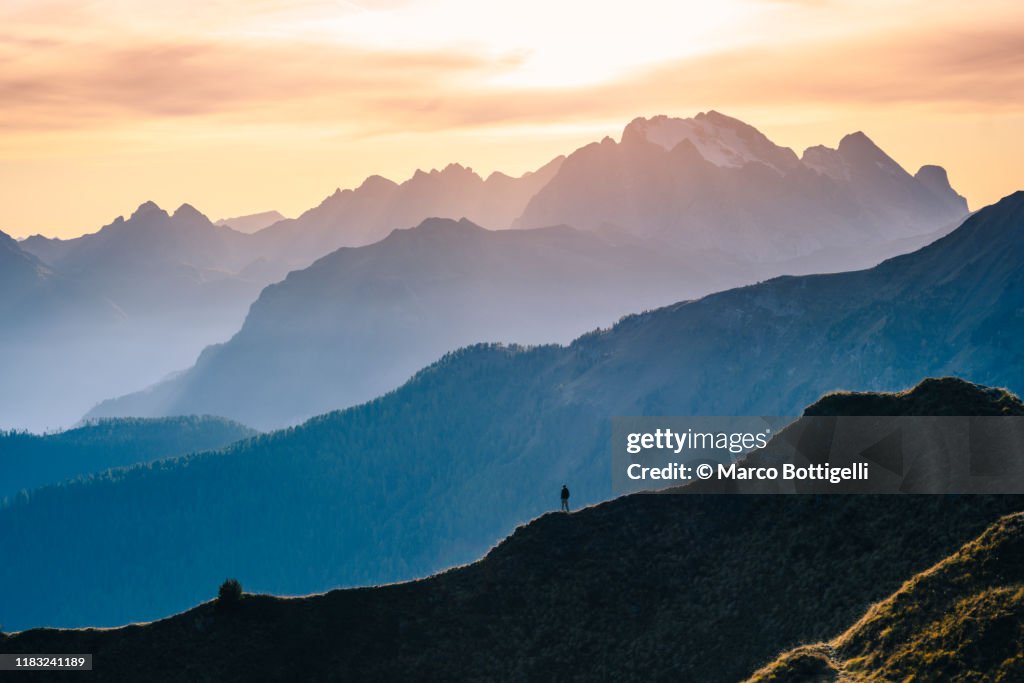 One person standing on a mountain ridge at sunset, Italy