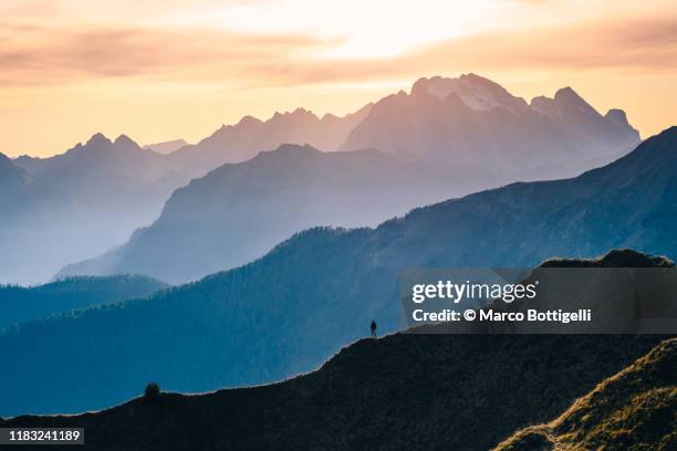 one person standing on a mountain ridge at sunset, italy - distant stock pictures, royalty-free photos & images