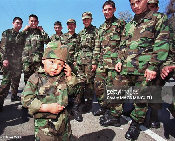 Child wearing a military uniform and exhausted from the intense heat, awaits the start of the military parade in Santiago, 19 September, 1999. The...
